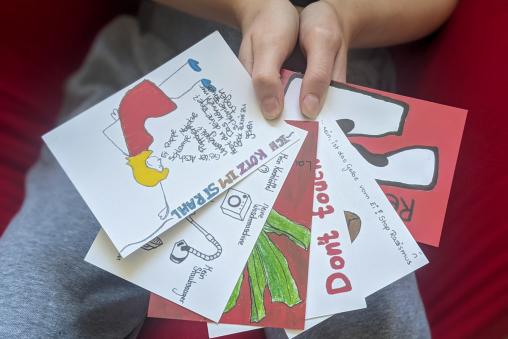 Eine Person hält fünf Postkarten mit verschiedenen Motiven wie einen Fächer 